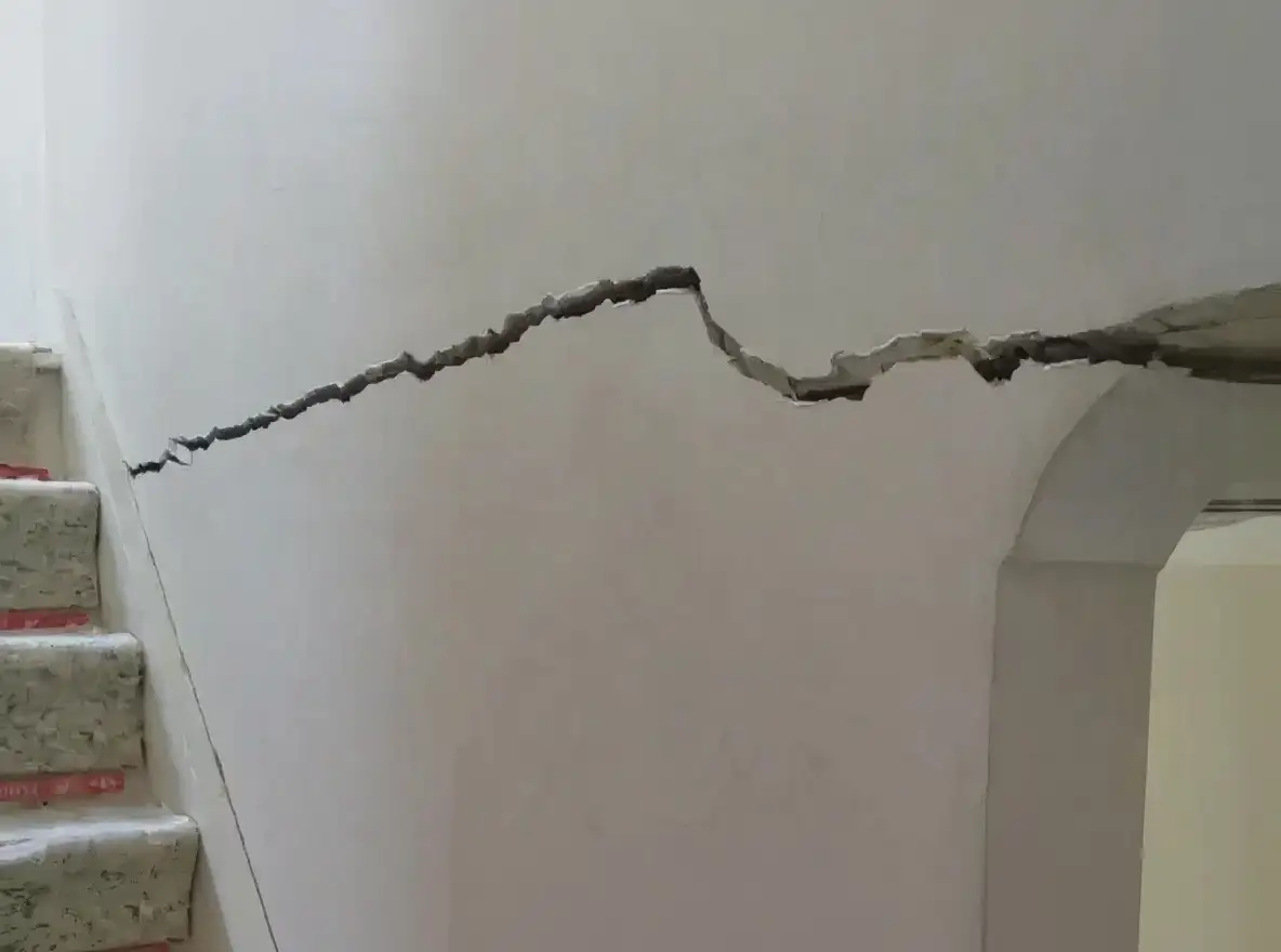 Interior door frame showing visible distortion from foundation movement — door no longer sits square with gaps at corners and drywall cracks extending from the frame